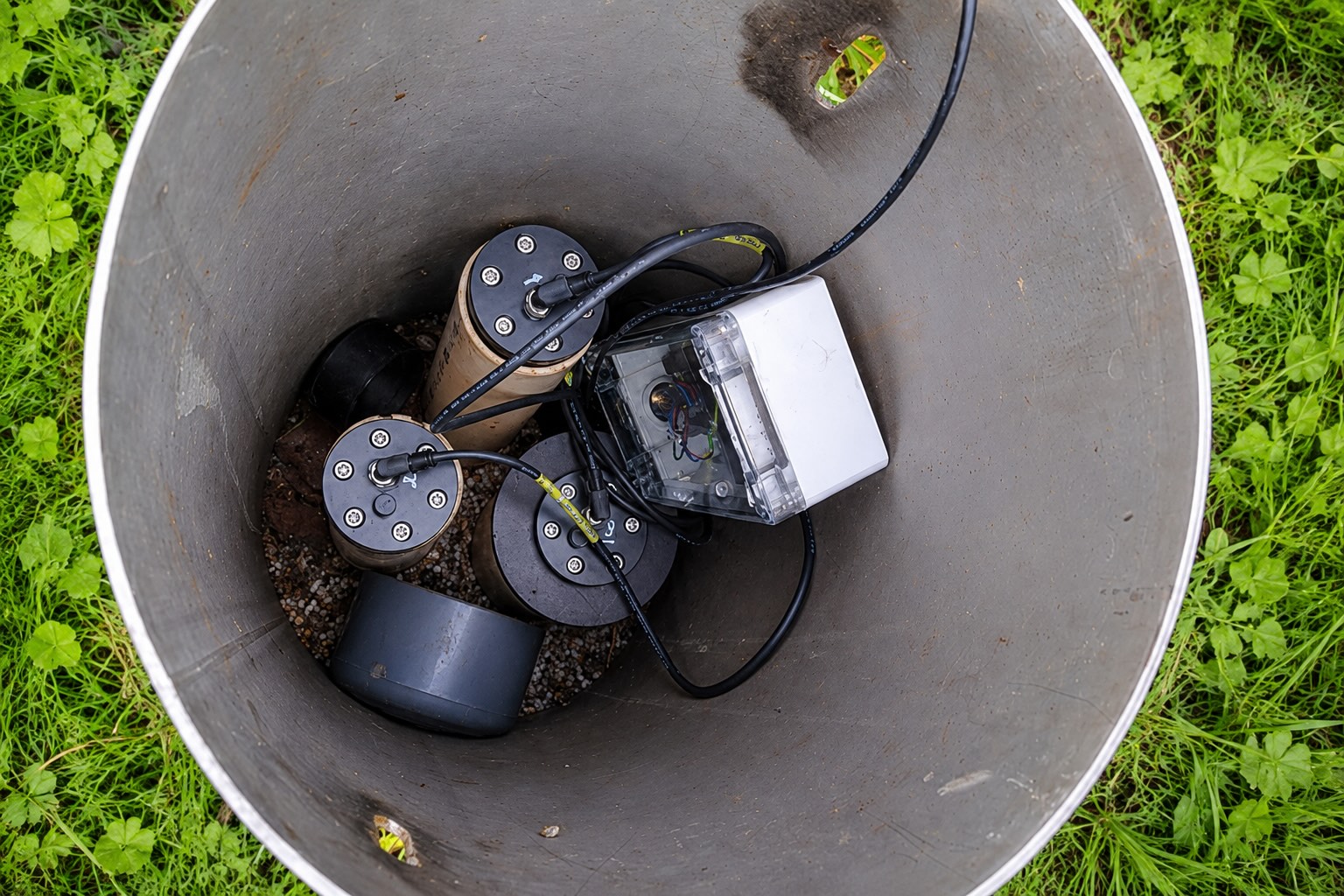 Blik in de beschermbuis van een grondwatermeetpunt, met drukopnemers, kabels en de IoT-module in een transparante behuizing